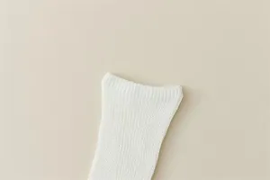 Close-up detail of soft white ribbed knit calf socks, classic casual hosiery texture.