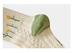 Detail view of women's knit mid-tube socks with cute flower patterns and green heel.