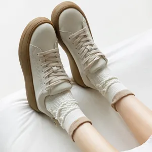 Gros plan de chaussettes en tricot vintage à motif torsadé et revers bouffant avec baskets.