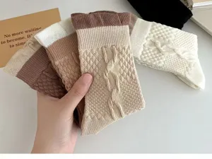 Gros plan sur les chaussettes en tricot avec poignets boules et motifs torsadés en café.