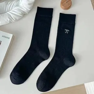 Close-up detail of black mid-calf socks with cute white bow design for daily wear.