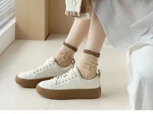 Vue détaillée de jolies chaussettes marron en maille torsadée avec baskets blanches.