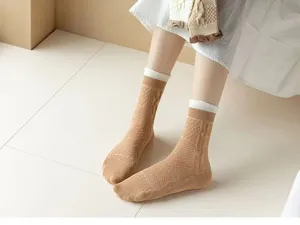 Vue rapprochée de chaussettes mi-hautes en tricot torsadé marron avec revers blancs.