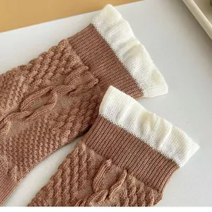 Gros plan de chaussettes marron en maille torsadée avec revers blancs, texture douce.