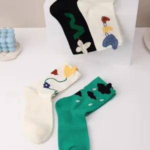 Mid-calf socks detail showing 3D heart and flower embroidery design on cotton fabric.
