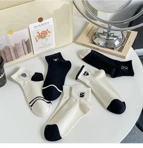 Black and white casual women socks detail view, showing cute embroidered patterns and soft fabric.