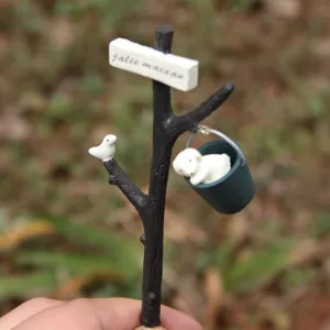 Detail view of miniature tree branch garden flower insert prop with cute dog and bird decor.
