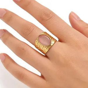 Nahaufnahme eines Vintage Gold Edelstahlrings mit einem rosa ovalen Stein an der Hand.