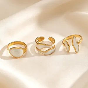 Detailopname van drie geometrische roestvrijstalen open ringen met witte druppels.