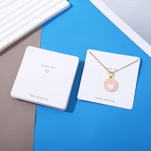 Close-up of white jewelry display cards with cute thank you text and a pink heart necklace.