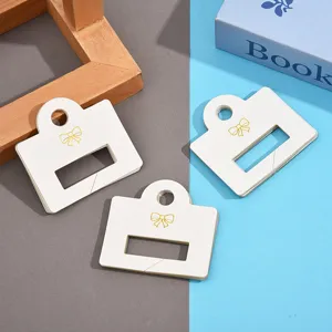 Cartes de présentation pour pinces à cheveux, cartes PVC blanches avec nœud doré élégant.