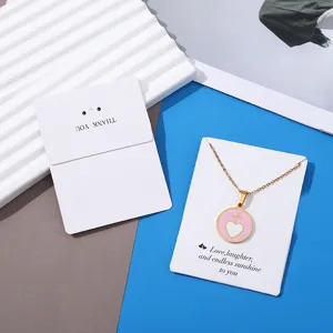 Gold heart necklace with pink enamel pendant and elegant white display card for jewelry packaging.