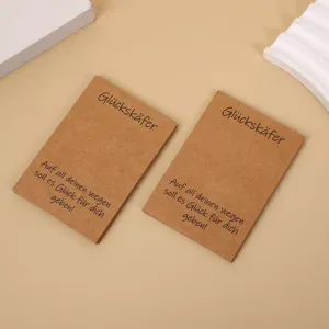 Vista dettagliata di biglietti auguranti in carta kraft, decorativi con testo.