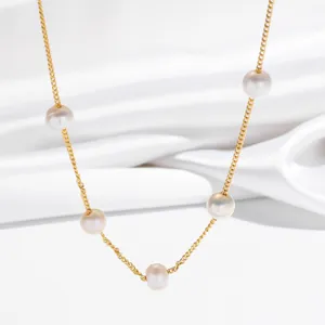 Close-up detail of a dainty gold chain necklace featuring evenly spaced white freshwater pearls.