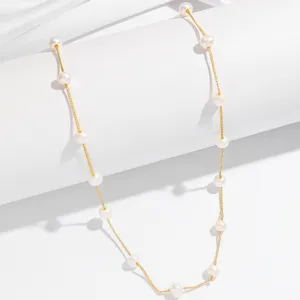 Close-up detail of the elegant French style pearl station necklace with delicate gold chain.