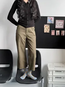 Detail shot of women's casual trousers and patterned mid-calf socks in indoor setting.