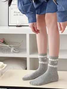 Close-up detail of gray cotton mid-calf socks featuring white bows and pearl embellishments.