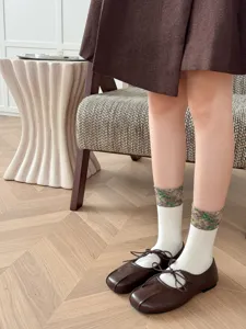Close-up of retro floral mid-calf socks paired with brown shoes in an indoor lifestyle setting.