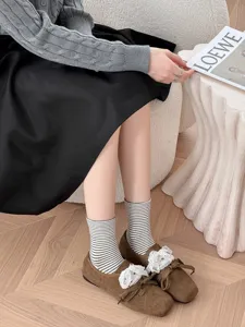 Detailed view of Japanese style striped socks paired with brown bow shoes in cozy room.