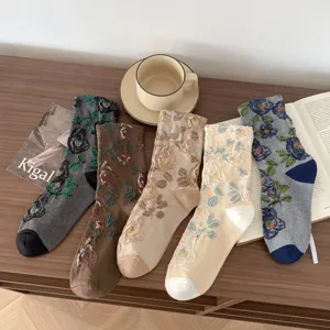 Detailed shot of womens vintage floral embroidered mid-tube socks on wooden table with aesthetic props.