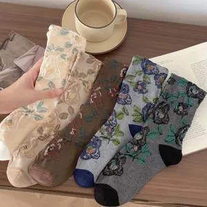 Detailed shot of vintage floral embroidered mid-calf socks in various colors on wooden table.