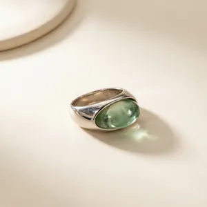 Primo piano dettaglio di un anello di modo in acciaio inossidabile con pietra di resina verde.