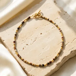 Close-up van de vintage kralenketting met gouden T-sluiting op een getextureerde steen.