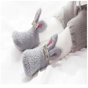Close-up of baby coral fleece socks featuring cute 3D rabbit ears and soft bow detail.