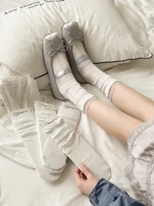 Detail view of women's white mid-calf ruffle stack socks paired with cute ballet flats.