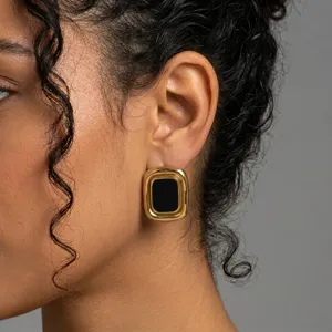 Close-up detail of retro geometric gold-rimmed earrings with black inlay, elegant design.