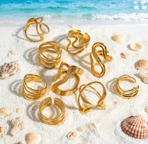 Detailaufnahme minimalistischer Edelstahl geometrische unregelmäßige Ringe am Sandstrand.