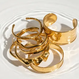 Detailansicht gestapelter goldener Armreifen mit unregelmäßiger Struktur und glänzendem Finish.