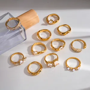 Primo piano di anelli in acciaio inossidabile dorato con zirconi brillanti e perle eleganti.