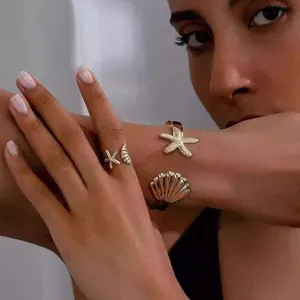 Detailaufnahme von goldenen Edelstahl Seestern und Muschel offenen Ring Armbänder Set.