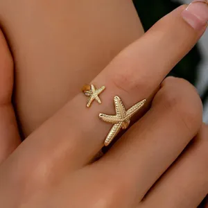 Detailaufnahme eines doppelten Seestern Offener Ring, goldener Edelstahl Ozean Stil Schmuck.