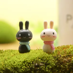 Close-up detail of cute miniature couple rabbit figurines on moss with colorful knit scarves.