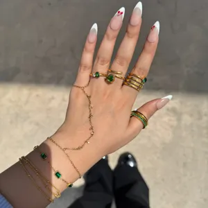 Vista detallada de anillos apilados de acero inoxidable dorado y pulsera de cadena de mano.
