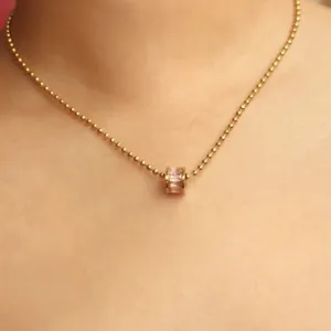 Zarte Goldperlen-Halskette mit einem kleinen rosa Kristall-Tonnenanhänger, Detailansicht.