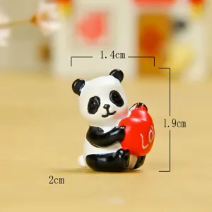 Detailed close-up view of a cute resin panda miniature holding a red heart ornament for desktop.