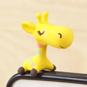 Cute cartoon giraffe phone dust plug detail shot, adorable yellow figurine ornament accessory.