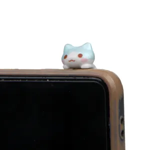 Detailed close-up view of a cute blue and white cat phone dust plug and mini charm accessory.