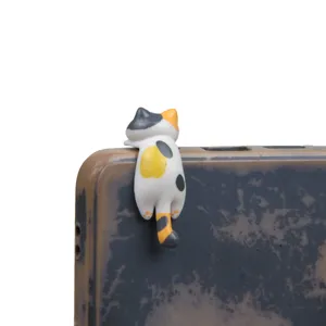 Cute cartoon calico cat phone charm detail, adorable miniature animal figurine for mobile device.