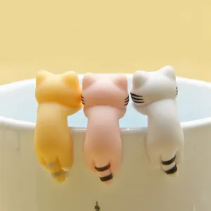 Closeup of cute hanging cat figurines, colorful resin animal charms for cup rim or phone.