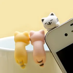 Close-up detail of cute cat figurines hanging on cup and phone edge, charming and fun decor.