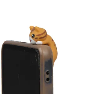 Cute orange cat phone dust plug detail shot, hanging on phone corner, resin material.