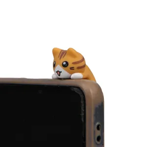 Cute orange cat phone dust plug detail shot, adorable animal figurine accessory for smartphone.