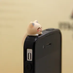 Cute cat phone dust plug accessory hanging on smartphone top main view product photo