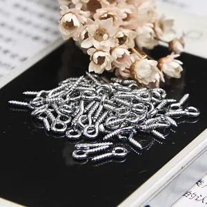 Nahaufnahme von silbernen Ösenschrauben und kleinen Schraubstiften für DIY-Schmuck.