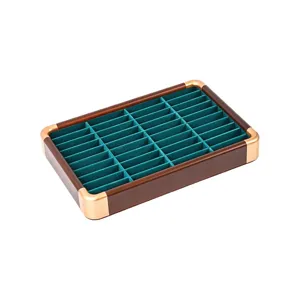 Walnut wood jewelry display tray with green velvet lining and gold corners for rings and bracelets.