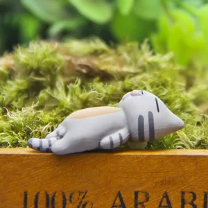 Gedetailleerde close-up van een schattig grijs gestreept kattenbeeldje op groen mos.